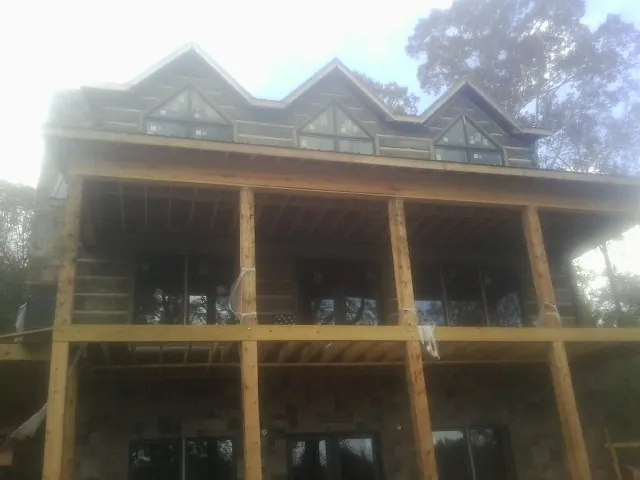 Dormers and porch framing on a large log home under construction — Roof Coating work by our crew in Suffield
