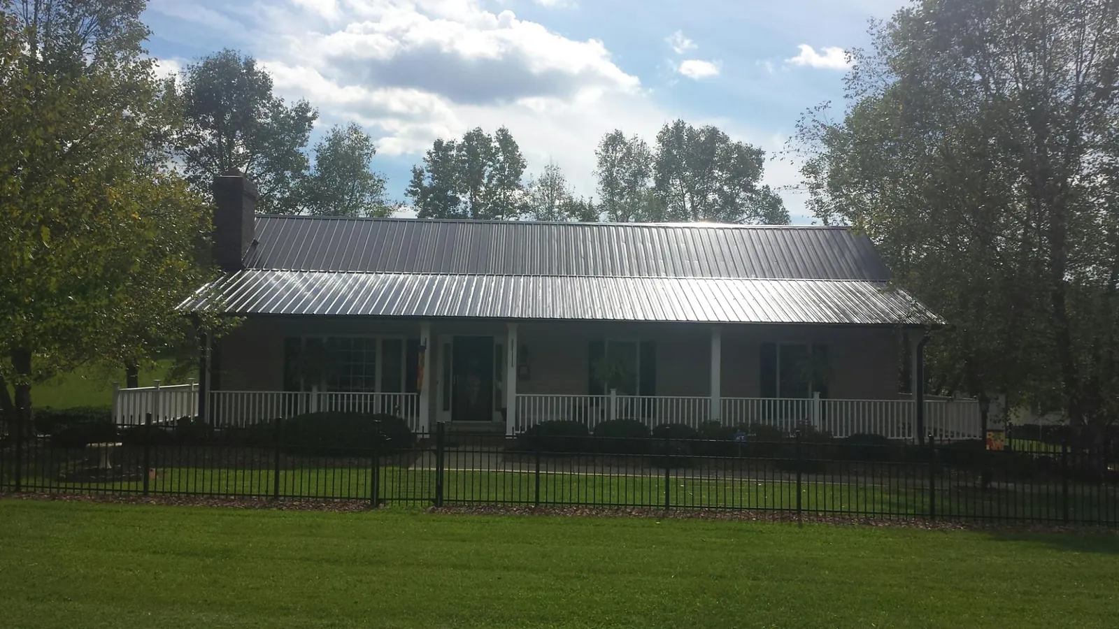 Gray metal roof on a brick ranch with a full width front porch — Gutter Guard Installation work by our crew in Suffield